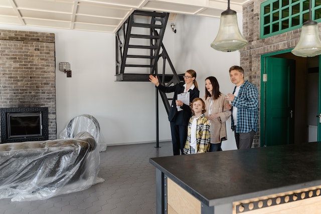 a small family and a person in a suit looking at a living room